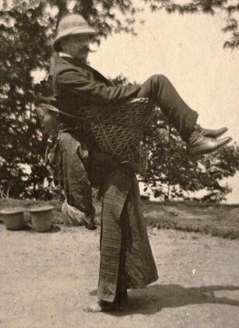 A Sikkimese Bhutia woman carrying a European man in a wicker basket, attributed to the Darjeeling–Sikkim region, early 1900s. Exact date, location and circumstances remain uncertain.